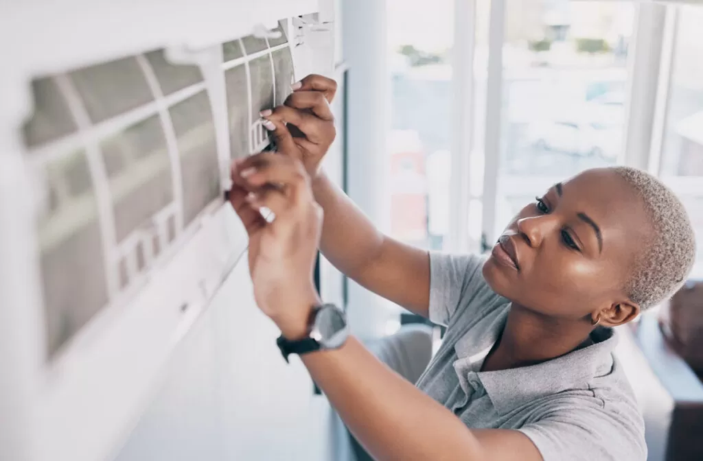 A professional performing a repair on an air conditioner on a wall of a North Fort Myers home.